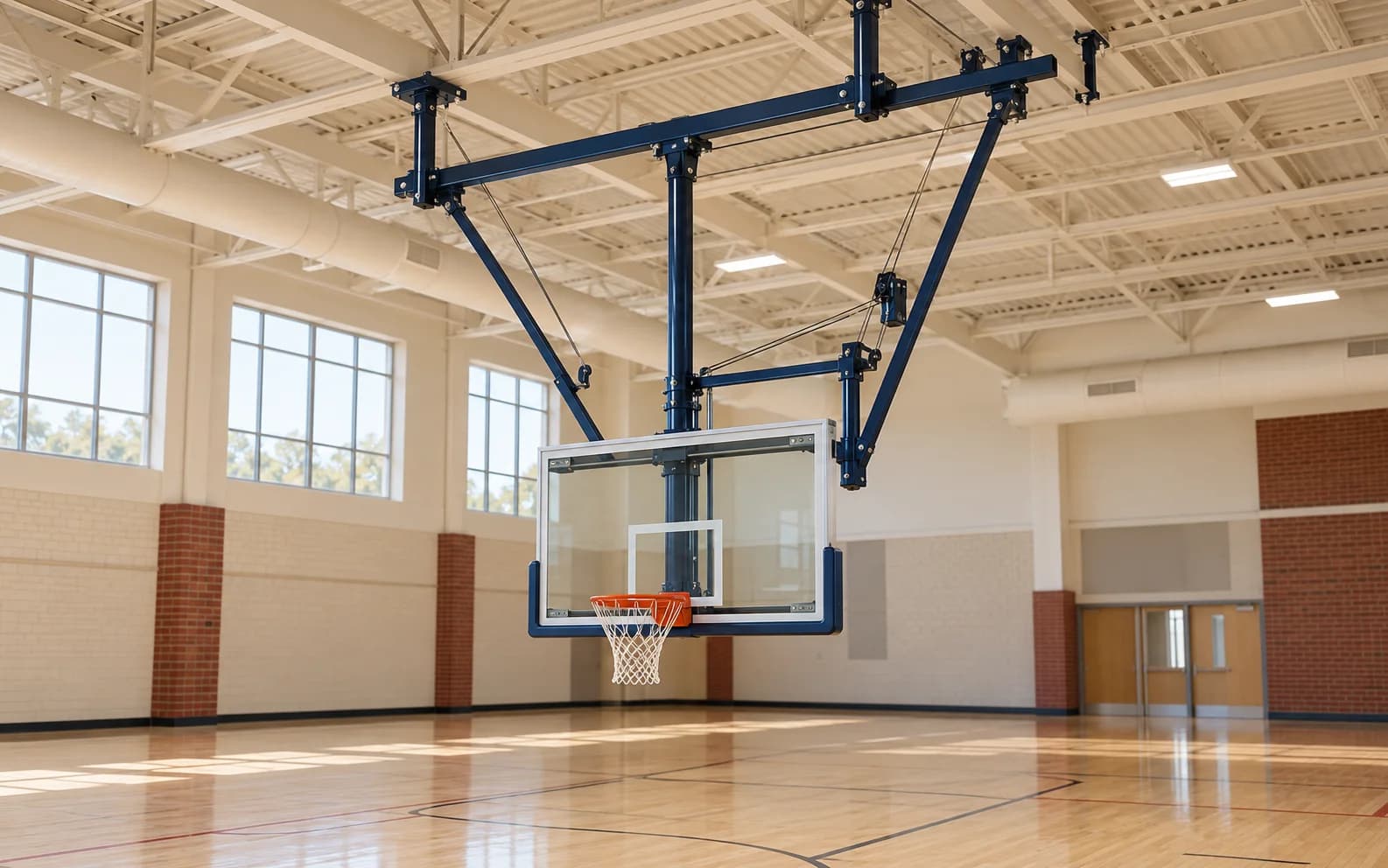 Navy ceiling-suspended basketball backstop photographed in an empty gym